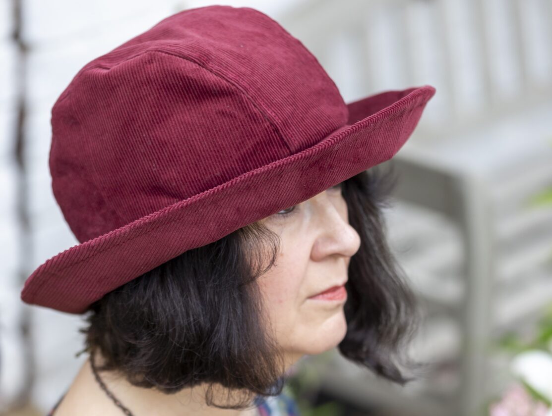 Emma in the Charlie's Aunt studio garden wearing a claret toned British corduroy Beckhythe Hat